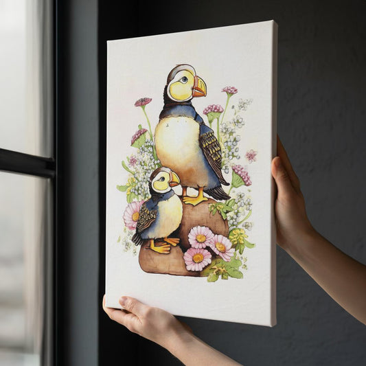 A person is holding up a canvas print featuring two colorful birds, likely seagulls, surrounded by flowers and plants.